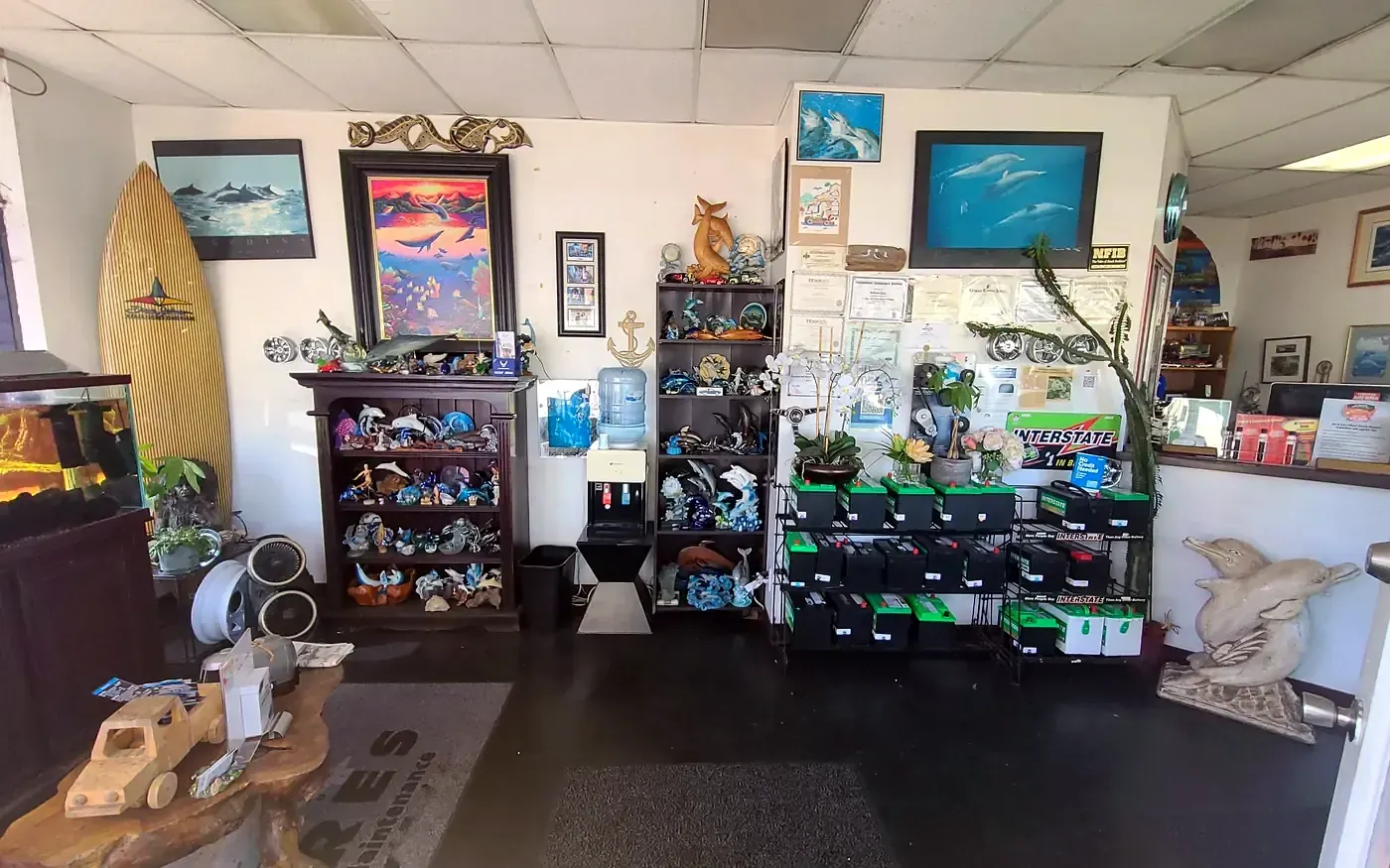 The front office at Beach Motor & Tires: dolphins, a surfboard, the fish tank and a rack of batteries