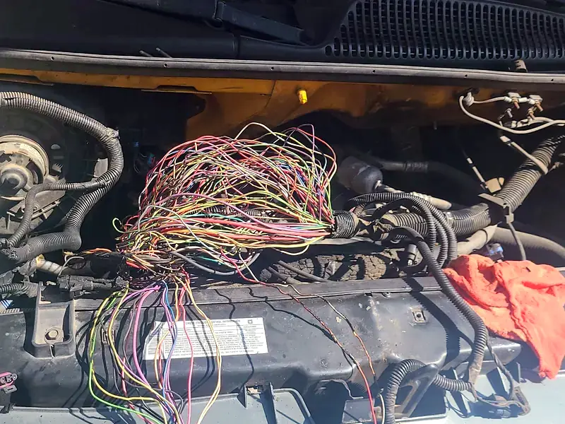 Engine harness and connectors laid out on a Chevy van during a repair